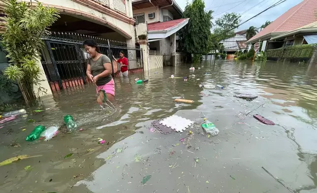 Residents walk outside their flooded homes as Typhoon Kalmaegi affects Cebu city, central Philippines, Tuesday Nov. 4, 2025. (AP Photo/Jacqueline Hernandez)