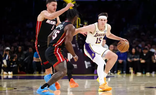 Los Angeles Lakers guard Austin Reaves (15) dribbles against Miami Heat forward Nikola Jovic (5) and guard Davion Mitchell, center, during the first half of an NBA basketball game, Sunday, Nov. 2, 2025, in Los Angeles. (AP Photo/Jessie Alcheh)