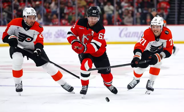 New Jersey Devils left wing Jesper Bratt (63) plays the puck against Philadelphia Flyers left wing Noah Cates (27) and right wing Tyson Foerster (71) during the second period of an NHL hockey game, Saturday, Nov. 29, 2025, in Newark, N.J. (AP Photo/Noah K. Murray)