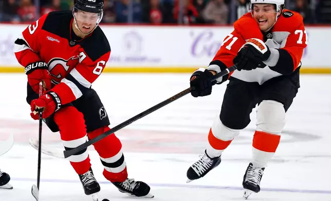 New Jersey Devils left wing Jesper Bratt (63) plays the puck against Philadelphia Flyers right wing Tyson Foerster (71) during the second period of an NHL hockey game, Saturday, Nov. 29, 2025, in Newark, N.J. (AP Photo/Noah K. Murray)