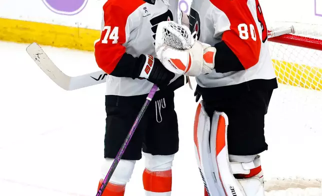 Philadelphia Flyers right wing Owen Tippett (74) and goaltender Dan Vladar (80) celebrate after defeating the New Jersey Devils in an NHL hockey game, Saturday, Nov. 29, 2025, in Newark, N.J. (AP Photo/Noah K. Murray)