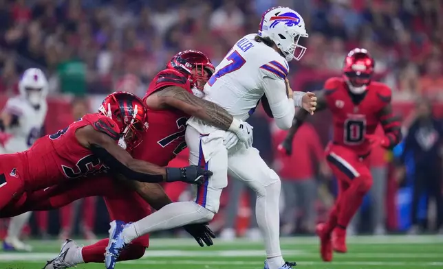 Houston Texans' Danielle Hunter, left, and Tommy Togiai, center, sack Buffalo Bills quarterback Josh Allen (17) in the second half of an NFL football game Thursday, Nov. 20, 2025, in Houston. (AP Photo/Ashley Landis)