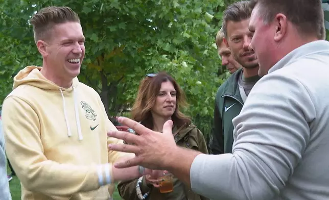 In this image made from video former Sparty mascots, Ross Ramsey, far left, Phil Lator, second from right, and Scott Ferry, far right, hang out at a pregame tailgate on Michigan State University campus, Sept. 6, 2025, in East Lansing, Mich. (AP Photo/Mike Householder)