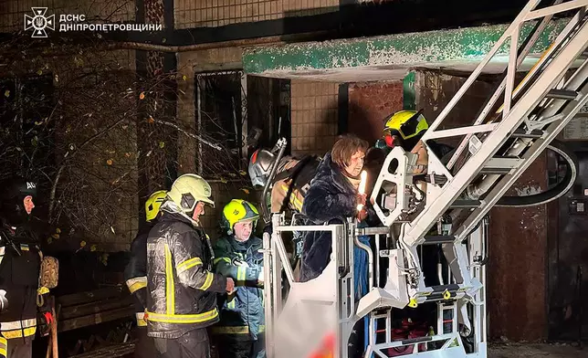 In this photo provided by the Ukrainian Emergency Service, firefighters evacuate a resident following a Russian rocket attack that hit a multi-storey apartment building in Dnipro, Ukraine, Saturday, Nov. 8, 2025. (Ukrainian Emergency Service via AP)