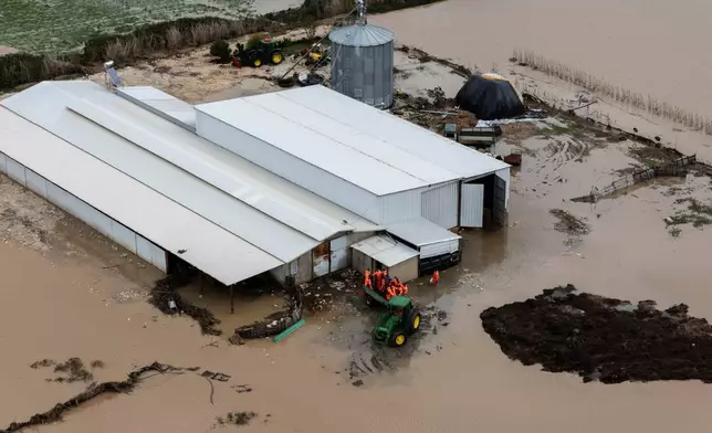 Emergency personnel assist in evacuating a flooded farm after a week of torrential rains in the town of Cuke near Sarande, southern Albania, Saturday, Nov. 22, 2025. (AP Photo/Vlasov Sulaj)