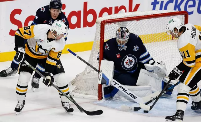 Pittsburgh Penguins' Sidney Crosby (87) makes the pass in front of Winnipeg Jets goaltender Eric Comrie (1) during the second period of an NHL hockey game, Saturday, Nov. 1, 2025, in Winnipeg, Manitoba. (John Woods/The Canadian Press via AP)