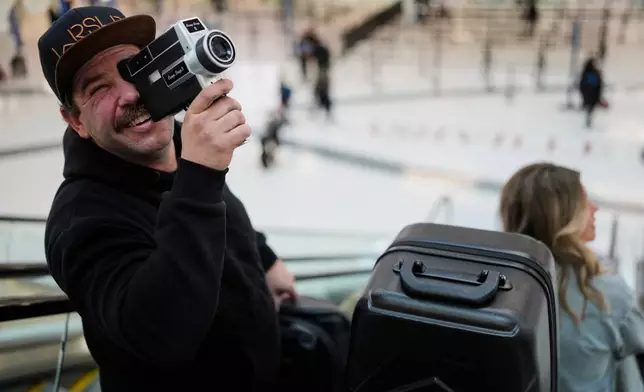 Jordan Heid uses an old film camera as he arrives for his flight at the Nashville International Airport, Tuesday, Nov. 25, 2025, in Nashville, Tenn. (AP Photo/George Walker IV)