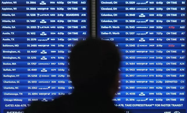 A traveler checks their airline flight at Detroit Metropolitan Wayne County Airport, Monday, Nov. 24, 2025, in Romulus, Mich. (AP Photo/Paul Sancya)