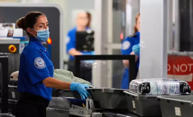 A TSA agent pushes bins along at a security checkpoint at the Dallas Fort Worth International Airport, at DFW Airport, Texas, Friday, Nov. 21, 2025. (AP Photo/Tony Gutierrez)