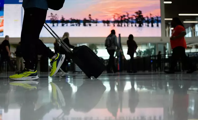 Travelers make their way through the Nashville International Airport, Tuesday, Nov. 25, 2025, in Nashville, Tenn. (AP Photo/George Walker IV)