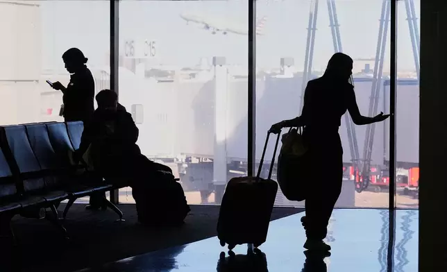 Travelers wait at a gate for their departing flight at the Dallas Fort Worth International Airport, at DFW Airport, Texas, Friday, Nov. 21, 2025. (AP Photo/Tony Gutierrez)
