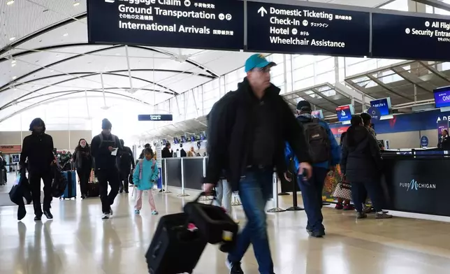 Travelers walk to their airline flights at Detroit Metropolitan Wayne County Airport, Monday, Nov. 24, 2025, in Romulus, Mich. (AP Photo/Paul Sancya)