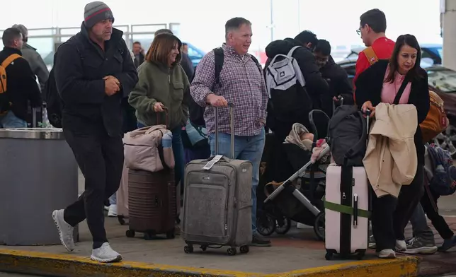 Travellers queue up for shuttle bus to car rental agencies outside the main terminal of Denver International Airport Tuesday, Nov. 25, 2025, in Denver. (AP Photo/David Zalubowski)
