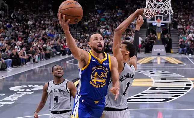 Golden State Warriors guard Stephen Curry (30) drives to the basket against San Antonio Spurs forward Victor Wembanyama (1) during the second half of an NBA Cup basketball game in San Antonio, Friday, Nov. 14, 2025. (AP Photo/Eric Gay)