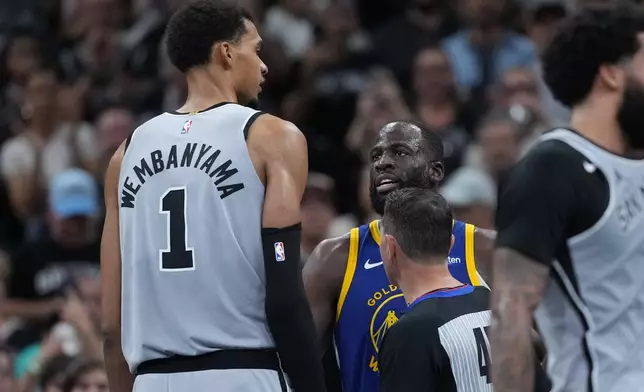 San Antonio Spurs forward Victor Wembanyama (1) and Golden State Warriors forward Draymond Green (23) trade words during the second half of an NBA Cup basketball game in San Antonio, Friday, Nov. 14, 2025. (AP Photo/Eric Gay)