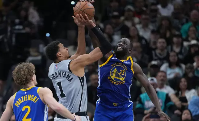 San Antonio Spurs forward Victor Wembanyama (1) is blocked by Golden State Warriors forward Draymond Green (23) during the second half of an NBA Cup basketball game in San Antonio, Friday, Nov. 14, 2025. (AP Photo/Eric Gay)