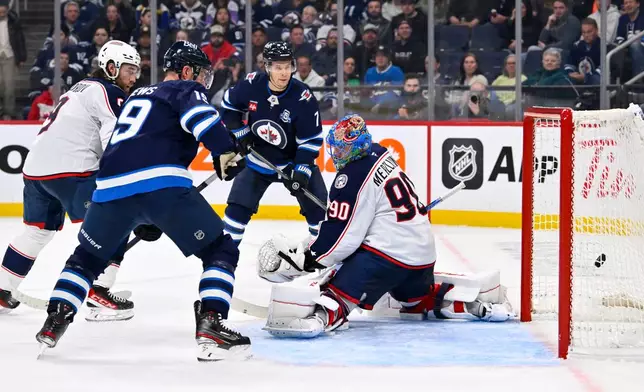 Columbus Blue Jackets goaltender Elvis Merzlikins is scored on by Winnipeg Jets' Neal Pionk during the second period of an NHL hockey game in Winnipeg, Manitoba, Tuesday Nov. 18, 2025. (Fred Greenslade/The Canadian Press via AP)