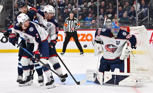 Columbus Blue Jackets goaltender Elvis Merzlikins (90) makes a save on a Winnipeg Jets shot as Jake Christiansen (2) and Dante Fabbro (15) defend against Jets' Vladislav Namestnikov (7) during the second period of an NHL hockey game in Winnipeg, Manitoba, Tuesday Nov. 18, 2025. (Fred Greenslade/The Canadian Press via AP)
