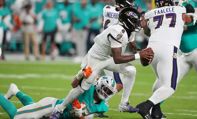 Baltimore Ravens quarterback Lamar Jackson (8) breaks free from the tackle of Miami Dolphins linebacker Jaelan Phillips (15) during the first half of an NFL football game, Thursday, Oct. 30, 2025, in Miami Gardens, Fla. (AP Photo/Lynne Sladky)