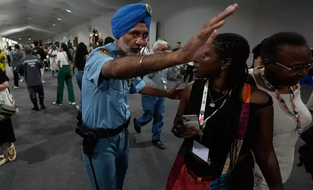 A security officer directs people to leave the venue for the COP30 U.N. Climate Summit, Thursday, Nov. 20, 2025, in Belem, Brazil. (AP Photo/Fernando Llano)