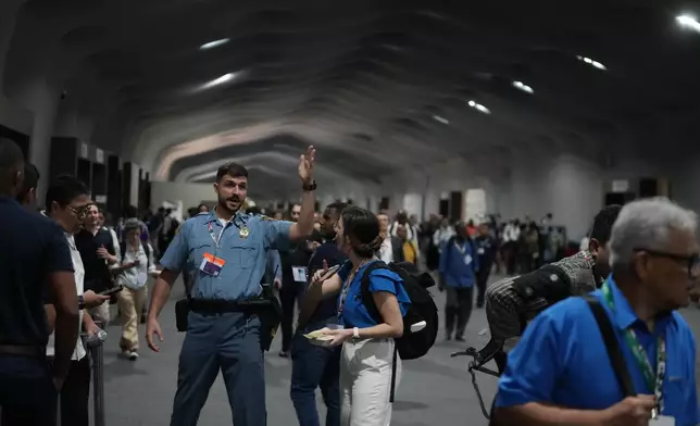 A security officer directs people to leave the venue for the COP30 U.N. Climate Summit, Thursday, Nov. 20, 2025, in Belem, Brazil. (AP Photo/Fernando Llano)