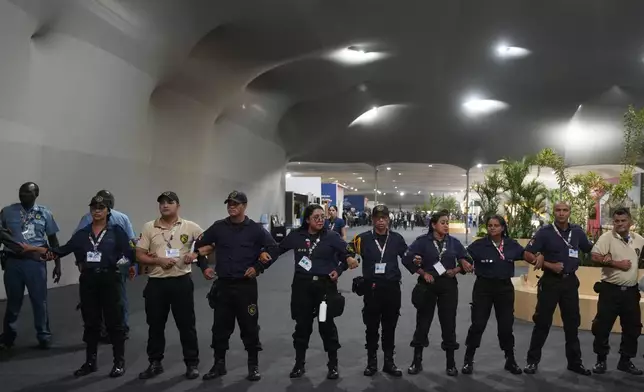 Officials form a chain to not allow attendees past after attendees were asked to leave the venue for the COP30 U.N. Climate Summit, Thursday, Nov. 20, 2025, in Belem, Brazil. (AP Photo/Andre Penner)