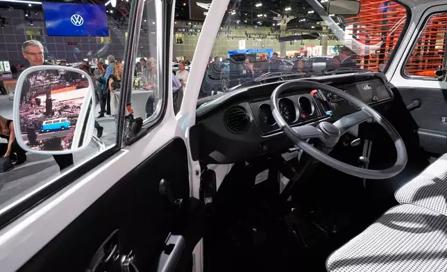 Convention-goers look over the restored VW bus, which had survived the Pacific Palisades fire in January, at the AutoMobility LA car show Thursday, Nov. 20, 2025, in Los Angeles. (AP Photo/Mark J. Terrill)