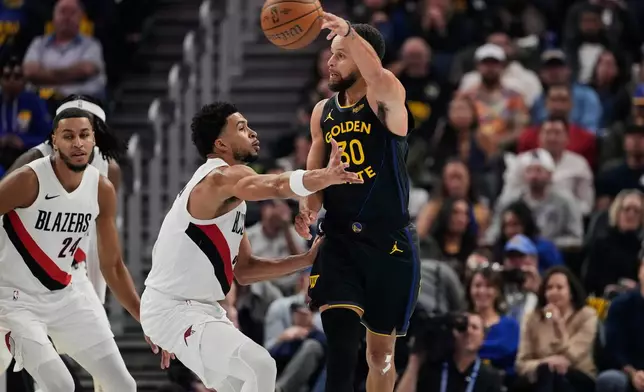 Golden State Warriors guard Stephen Curry (30) passes the ball while defended by Portland Trail Blazers forward Toumani Camara (33) during the first half of an NBA Cup basketball game, Friday, Nov. 21, 2025, in San Francisco. (AP Photo/Godofredo A. Vásquez)