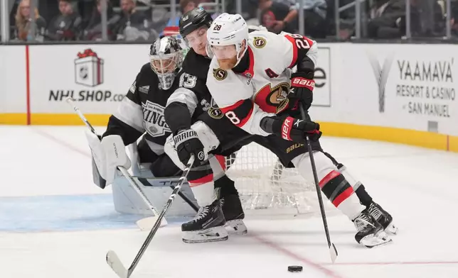 Ottawa Senators right wing Claude Giroux (28) moves the puck under defense by Los Angeles Kings defenseman Jacob Moverare (43) during the third period of an NHL hockey game Monday, Nov. 24, 2025, in Los Angeles. (AP Photo/Jae C. Hong)