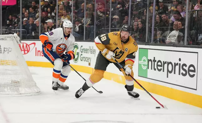 Vegas Golden Knights center Tomas Hertl (48) skates with the puck against New York Islanders defenseman Alexander Romanov (28) in the second period of an NHL hockey game Thursday, Nov. 13, 2025, in Las Vegas. (AP Photo/Candice Ward)