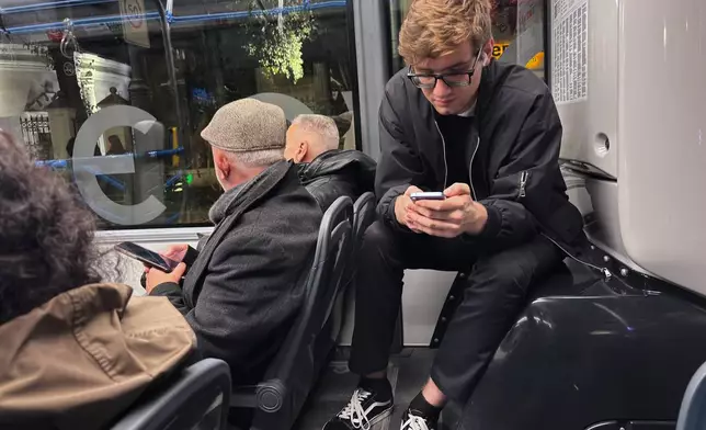 FILE - Passengers look at their smartphones on a bus in Moscow, Oct. 23, 2025. (AP Photo/Alexander Zemlianichenko, File)