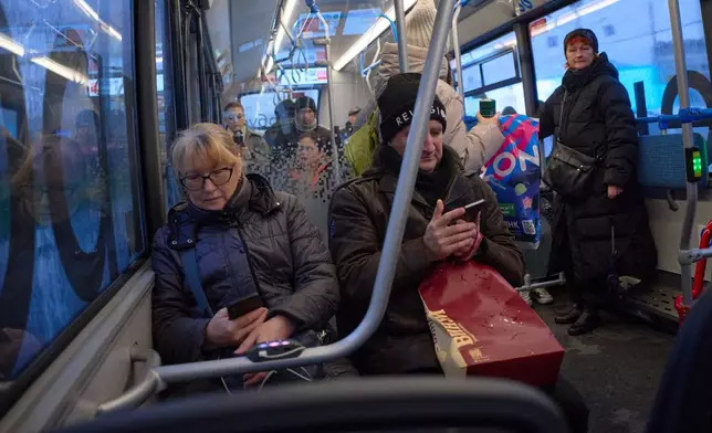 FILE - Passengers look at their smartphones on a bus in Moscow, Russia, Nov. 17, 2025. (AP Photo/Alexander Zemlianichenko, File)