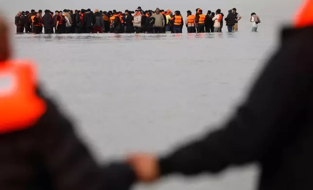 Migrants push a small boat in an attempt to reach Britain, Thursday, Nov. 6, 2025 in Gravelines, northern France. (AP Photo/Jean-Francois Badias)