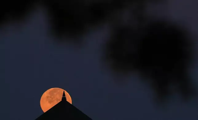 The full beaver supermoon sets beyond an office building Wednesday, Nov. 5, 2025, in Overland Park, Kan. (AP Photo/Charlie Riedel)
