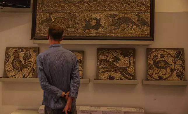 A visitor looks at ancient mosaics on display at the National Museum of Syria in Damascus, Friday, May 23, 2025. (AP Photo/Ghaith Alsayed)