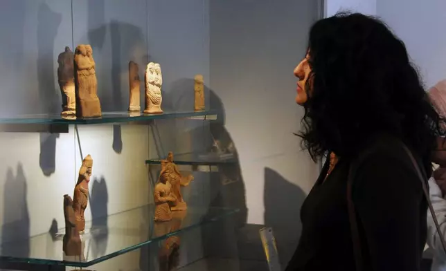 FILE - In this photo released by the Syrian official news agency SANA, a visitor looks at ancient artifacts during the reopening ceremony for Syria's National Museum, in Damascus, Syria, Oct. 28, 2018. (SANA via AP, File)