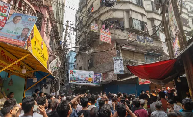 People gather outside a narrow lane in old city area where a roof and wall collapsed, after an earthquake in Dhaka, Bangladesh, Friday, Nov. 21, 2025. (AP Photo/Abdul Goni)