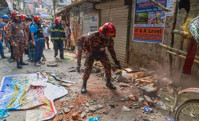 A rescue official clears the debris from roof and wall collapse after an earthquake in Dhaka, Bangladesh, Friday, Nov. 21, 2025. (AP Photo/Abdul Goni)