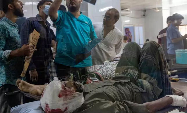 A doctor inspects an X-ray of a patient injured in an earthquake at a hospital in Dhaka, Bangladesh, Friday, Nov. 21, 2025. (AP Photo/Abdul Goni)