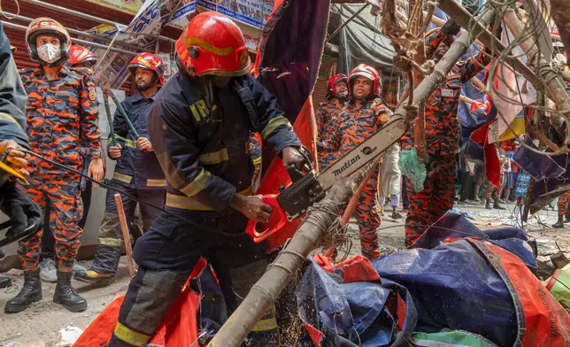 Rescue and fire officials cut building railings falling on the street to make way after an earthquake in Dhaka, Bangladesh, Friday, Nov. 21, 2025. (AP Photo/Abdul Goni)