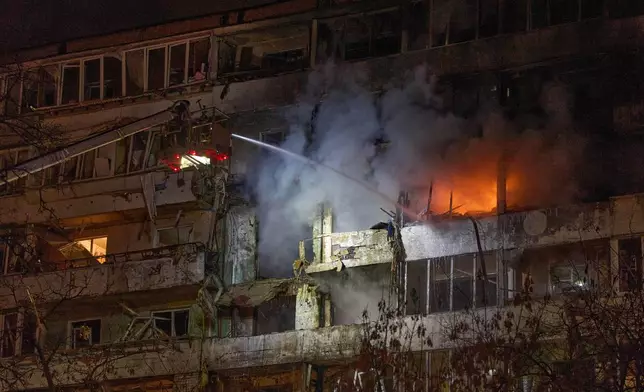 Firefighters put out the fire after a drone hit a multi-storey residential building during Russia's night drone attack in Kyiv, Ukraine, Tuesday, Nov. 25, 2025. (AP Photo/Efrem Lukatsky)