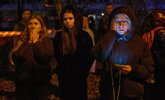 Local residents react as they watch their burning home after a drone hit a multi-storey residential building during Russia's night drone attack in Kyiv, Ukraine, Tuesday, Nov. 25, 2025. (AP Photo/Efrem Lukatsky)