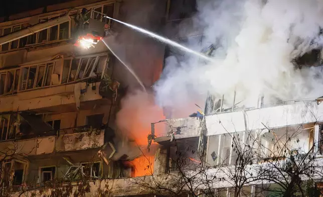 Firefighters put out the fire after a drone hit a multi-storey residential building during Russia's night drone attack in Kyiv, Ukraine, Tuesday, Nov. 25, 2025. (AP Photo/Efrem Lukatsky)