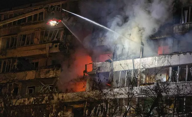 Firefighters put out the fire after a drone hit a multi-storey residential building during Russia's night drone attack in Kyiv, Ukraine, Tuesday, Nov. 25, 2025. (AP Photo/Efrem Lukatsky)