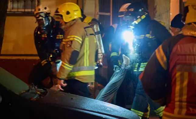 Rescuers carry the body of a civilian who was killed as a drone hit a multi-storey residential building during Russia's night drone attack in Kyiv, Ukraine, Tuesday, Nov. 25, 2025. (AP Photo/Efrem Lukatsky)