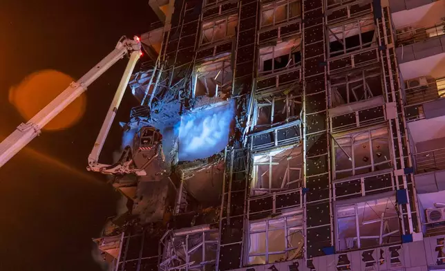 Emergency services personnel work to extinguish a fire following a Russian attack in Kyiv, Ukraine, Tuesday, Nov. 25, 2025. (AP Photo/Dan Bashakov)
