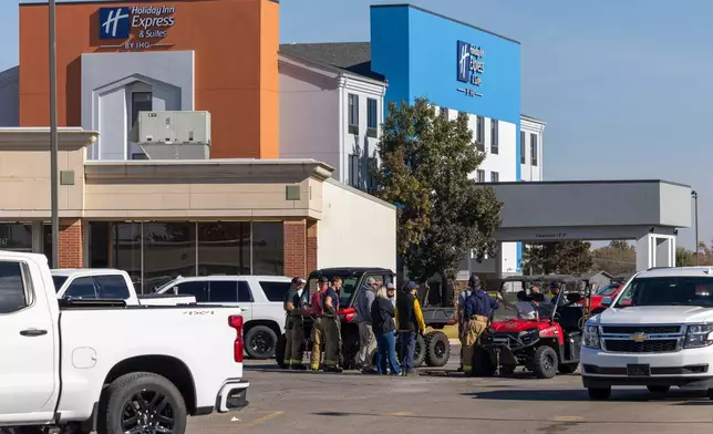 Business owners and first responders gather in a shopping center parking lot near the scene of an ammonia spill in Weatherford, Okla. after the shelter in place was lifted on Thursday, Nov. 13, 2025. (AP Photo/Alonzo Adams)