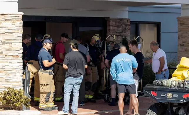 Fire crews bring down guest belongings from their hotel room at the Holiday Inn Express after the evacuation and shelter in place was lifted after a tanker truck had an ammonia gas leak in Weatherford, Okla. on Thursday, Nov. 13, 2025. (AP Photo/Alonzo Adams)