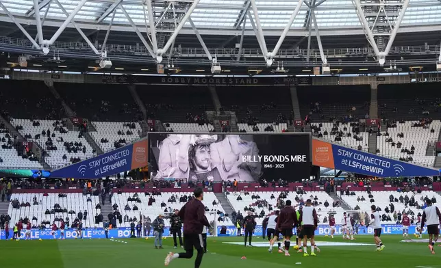 A giant screen displays a Wast Hum legend Billy Bonds dies aged 79 as players warm up prior to the start of the English Premier League soccer match between West Ham United and Liverpool, in London, Sunday, Nov. 30, 2025. (AP Photo/Kirsty Wigglesworth)