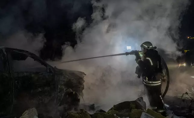 Rescue workers put out a fire of a residential building damaged by a Russian strike in Kharkiv, Ukraine, late Sunday, Nov. 23, 2025. (AP Photo/Andrii Marienko)